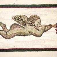 Embroidered image of a cherub playing a trumpet.
