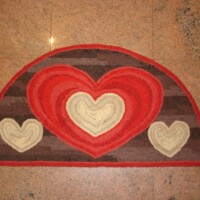 Half-moon shaped mat with heart patterns on a tiled floor.