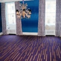 Interior room with blue walls, patterned purple carpet, and a hanging chandelier.