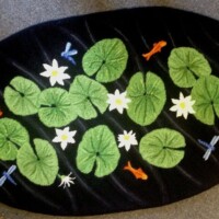 handmade rug with lily pad & fish pond scene on black background