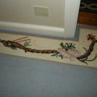 Decorative rug with floral and fauna motifs lying on a blue carpeted floor.