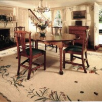 Traditional dining room with floral carpet, wooden table, chairs, and fireplace.