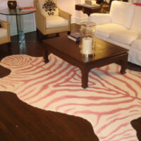 A living room with a zebra-patterned rug, a wooden coffee table, and white sofas.