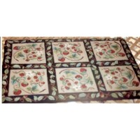 A patterned tablecloth with fruit and leaf designs on a wooden table.