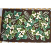 Rectangular latch hook rug featuring a floral pattern with green leaves and white flowers on a brown background.
