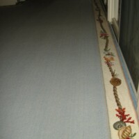 A carpeted hallway with a decorative border featuring leaf and acorn motifs.