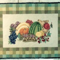 Colorful woven rug with a fruit and vegetable pattern and a checkered border.
