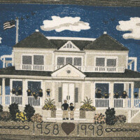 Embroidered depiction of a classical two-story house with a flag, clouds, and the years 1958 and 1998 stitched below.