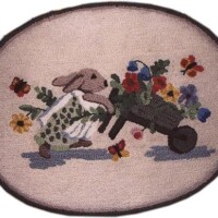 A rug featuring an embroidered design of a rabbit pushing a wheelbarrow full of flowers.