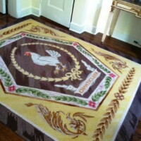 An ornamental rug with an rooster and floral designs on a wooden floor.