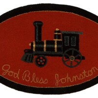An embroidered oval rug featuring a vintage train design with the text "god bless johnston.