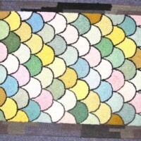 Colorful fish scale pattern rug on a floor.