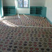 Empty room with patterned carpeting and built-in turquoise shelves.
