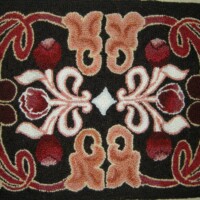 Floral patterned rug with symmetrical design in red, pink, and beige tones.