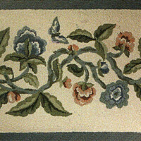Embroidered floral pattern with blue and peach flowers on a dark background.