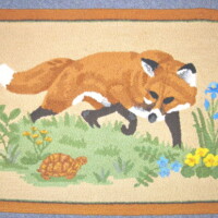 Embroidered fox and turtle on a decorative mat.