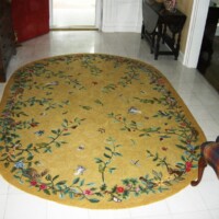 An oval floral-patterned rug on a tiled floor in a home interior.