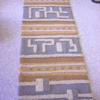 Long patterned carpet runner with geometric designs in shades of brown and beige.