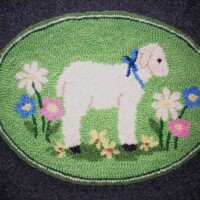 Hooked rug with a sheep and floral design on an oval background.