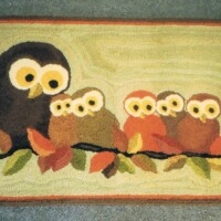A rug featuring a design of owls perched on a branch.