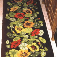 A hand hooked brown rug with nasturtium flowers by GW Ruggery.