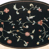 An elliptical black rug with floral embroidery designs in various colors.