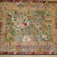 Handmade floral-patterned rug displayed on a wooden surface.