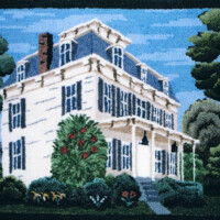 A needlepoint depiction of a two-story vintage house with surrounding trees.