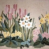 A needlepoint tapestry featuring a variety of embroidered flowers in bloom.