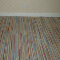 A room corner with striped carpet and floral wallpaper.