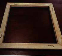 Wooden picture frame with no artwork mounted, set against a dark background.