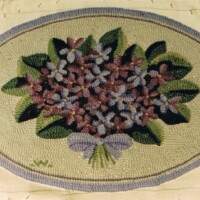 Oval floral rug with a green border on a yellow patterned background.